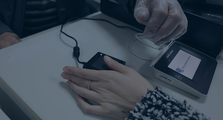 Coleta de biometria do dedo polegar da mão esquerda. Sobre uma mesa branca de trabalho aparece o...