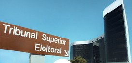 A imagem mostra uma placa de sinalização marrom com a inscrição “Tribunal Superior Eleitoral” e ...