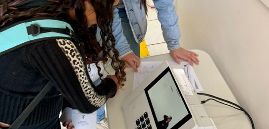 Três eleitoras vendo e manuseando a urna eletrônica