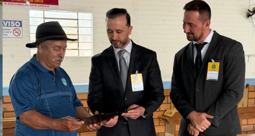 Imagem do juiz eleitoral e do promotor eleitoral entregando certificado de mérito eleitoral ao a...