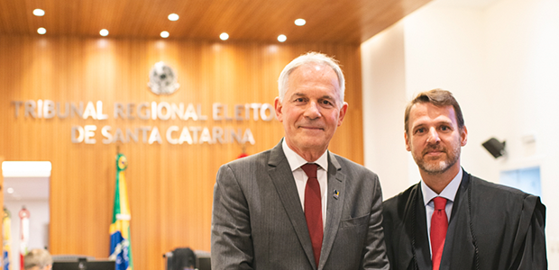 TRE-SC-Juiz-término-biênio-Ítalo Foto do presidente do TRE-SC com o juiz do Pleno. Dois homens brancos, usando termo e toga, lado...