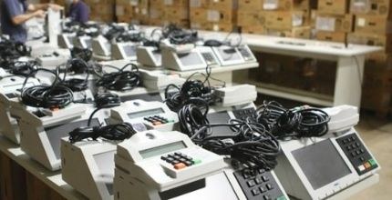 Urna Eletrônica completa 25 anos nesta quinta-feira, 13/5 #PraTodosVerem
Foto registrada em um ângulo lateral. À esquerda, urnas eletrônicas estão expo...